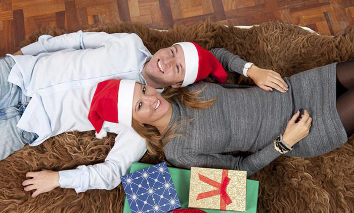 Young Happy Couple with Presents on rug at Christmas